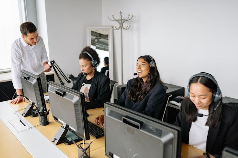 A diverse team of customer service representatives working in an office setting, wearing headsets and using computers.
