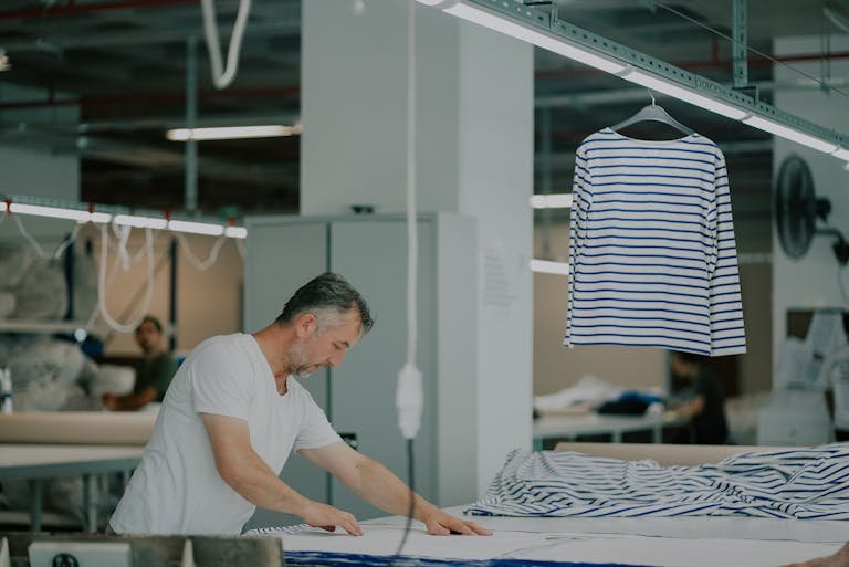 Adult male in a textile workshop working with striped fabric indoors.